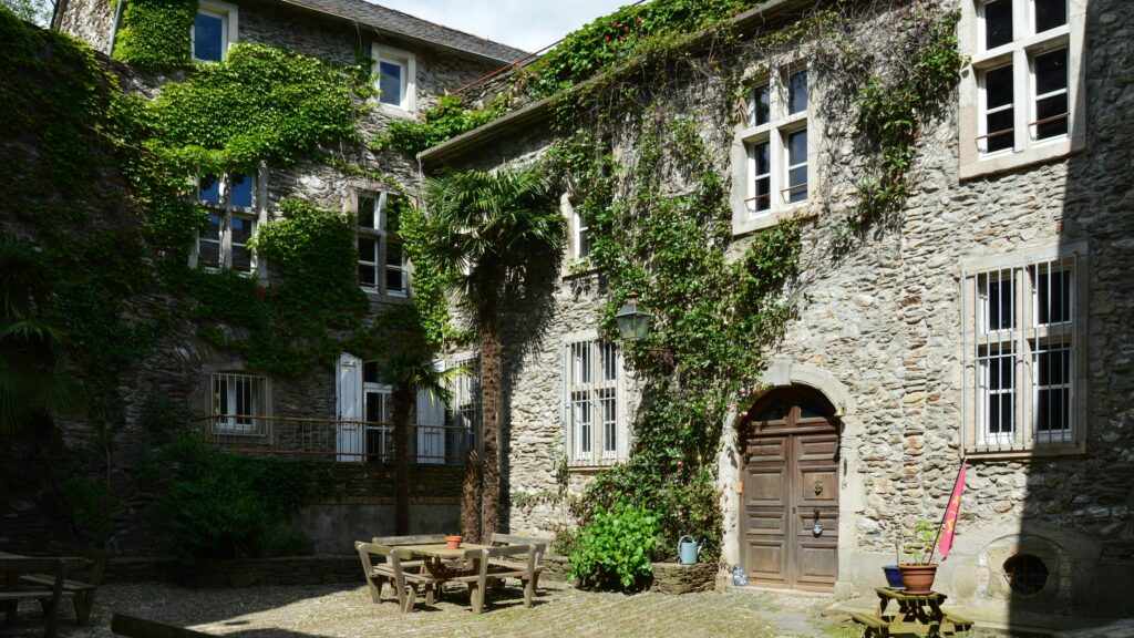 Rustic stone courtyard with ivy-covered walls and outdoor seating in Saint-Étienne-Vallée-Française, Occitanie.